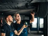 Ames aftersales twee monteurs onder een auto